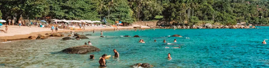 Pessoas nadando em praia de águas turquesas em Ilhabela